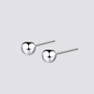 Macro detail of high-polished silver round ball stud earrings on a grey background