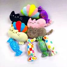 Flat lay of colorful cat plush toys and candy-shaped accessories on a grey surface