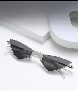 Detail of silver cat-eye metal sunglasses with dark gray triangle lenses on a white block