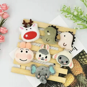 Detailed view of various cute plush animal pins including dinosaurs and elephants on a wooden fence