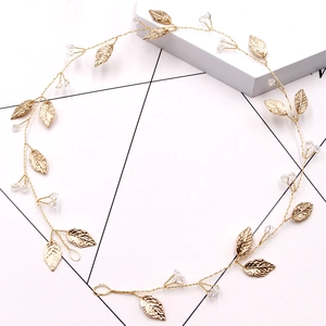 Detail of gold bridal hair comb with metallic leaves and sparkling crystal beads
