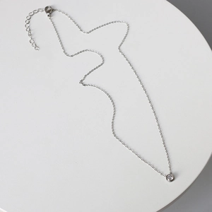 Detail of silver chain necklace featuring a round bezel-set sparkling zircon pendant