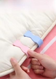 Detail of pink bow quilt clip securing a white duvet to prevent slipping on bed