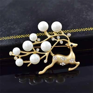 Close-up of reindeer brooch with golden antlers, white pearls and sparkling crystals