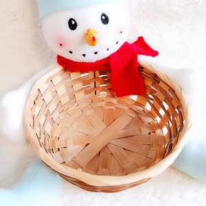 Detail of woven bamboo Christmas candy basket featuring a cute snowman plush character