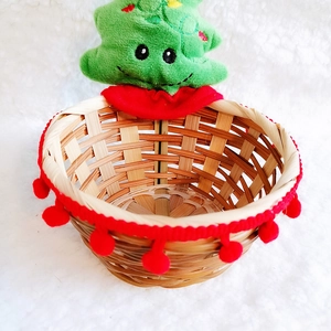 Detail view of a woven bamboo Christmas basket with plush tree and red pompom trim