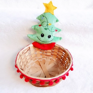 Detail of bamboo Christmas basket with red pom-poms and a plush green tree topper