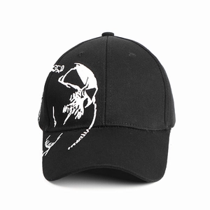 Detailed close-up of white skull embroidery on black cotton baseball cap front
