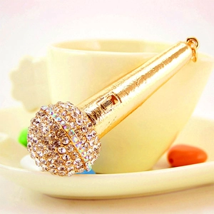 Sparkling gold microphone keychain with clear rhinestones on white tea cup background