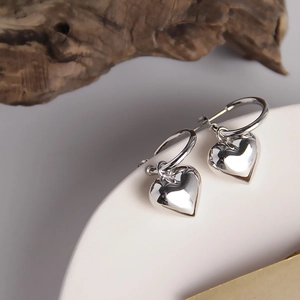 Nahaufnahme von minimalistischen S925 Sterlingsilber Creolen mit massiven Herzanhängern