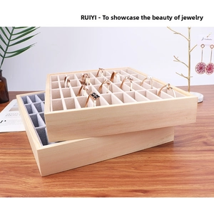 Detailed view of stacked wooden jewelry trays with grey velvet slots for rings and bracelets