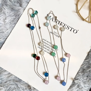Macro shot of long silver chain necklace with multi-colored square crystal pendants