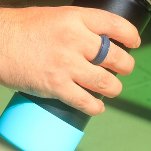 Close-up of a dark silicone ring with Greek key pattern on a man holding a cup
