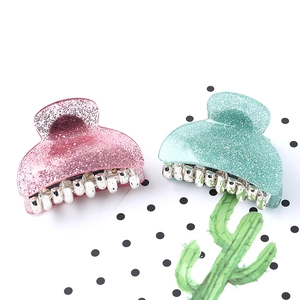 Close-up of pink and green glittery acrylic hair claws with silver metal teeth