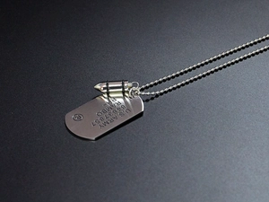 Detail of silver bullet pendant and US Army military dog tag on ball chain necklace