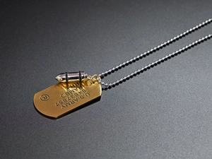 Detail of hip hop dog tag necklace with RAMBO engraving and silver bullet pendant