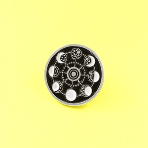 Detailed view of enamel celestial pin showing moon phase cycles and geometric star chart