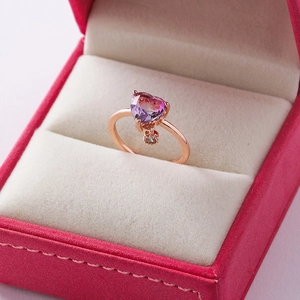 Close-up of heart-shaped pink crystal ring with micro-pave charms in a velvet jewelry box