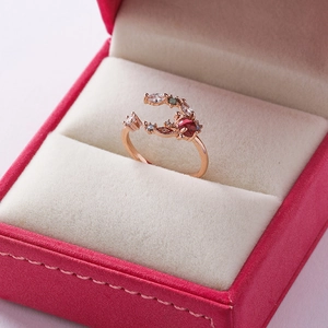 Macro view of rose gold floral ring with red zircon in a pink velvet jewelry gift box