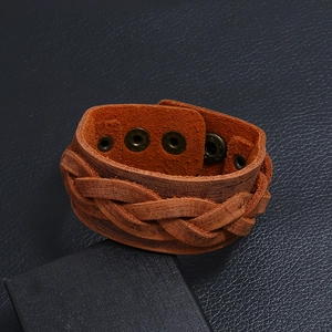 Macro detail of brown braided leather bracelet with silver-tone snap button closure