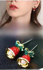 Detailed close-up of bowknot bell earrings with red crystals, green bow and white pearl