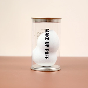 White gourd makeup puff in a clear cylindrical gift box with metal lid and base