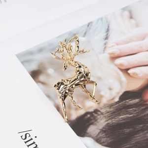 Macro shot of a gold geometric reindeer brooch on a stylish fashion magazine background