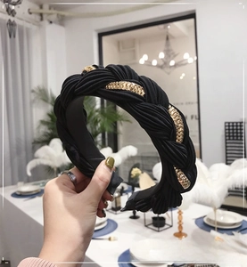 Dettaglio di un cerchietto nero intrecciato con catena in metallo dorato integrata
