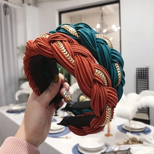 Terracotta and dark green pleated headbands with golden chain detail shown in hand