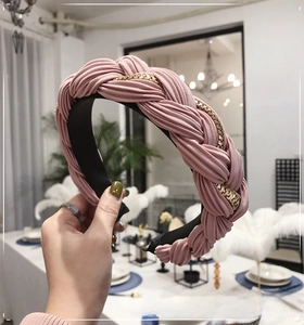 Dettaglio del cerchietto in tessuto a pieghe rosa intrecciato con catena dorata
