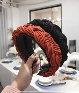 Detail view of braided twist headbands in orange and black with pleated fabric texture