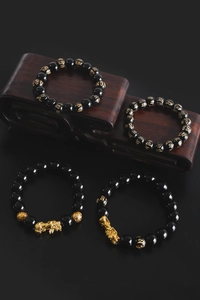 Macro detail of obsidian beads with gold Pixiu and engraved mantra characters
