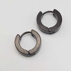 Détail d'une paire de boucles d'oreilles rondes en métal noir brossé et texture mate