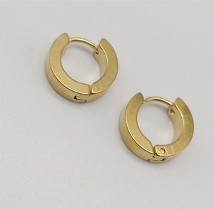 Vue macro de boucles d'oreilles créoles dorées avec finition en métal brossé
