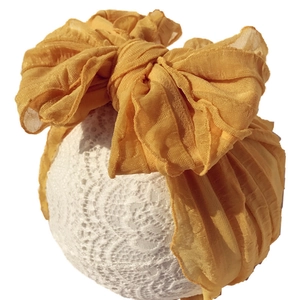 Ginger yellow baby headband featuring a large mesh bow and soft pleated texture