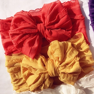 Detail of red and yellow baby headbands with large textured chiffon layered bows