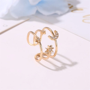 Detail of gold spiral ring featuring zircon inlaid star and moon on white background