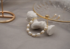 Detail view of Baroque freshwater pearl bracelet with golden beads and sliding clasp