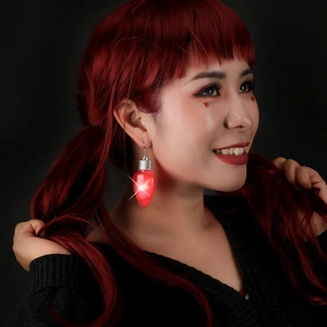 Detail view of glowing red bulb Christmas earrings with silver hooks on a model
