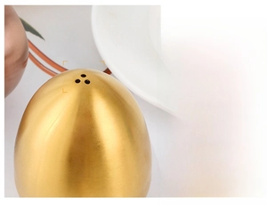 Macro shot of the three-hole spray design on a golden brushed stainless steel egg shaker