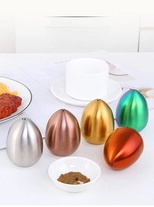 Egg-shaped stainless steel seasoning shakers set in five metallic colors on a dining table