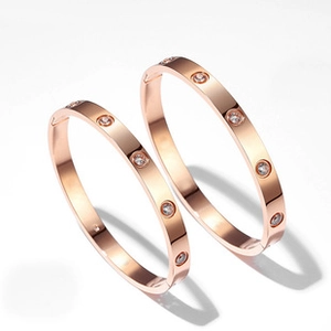 Detailed view of rose gold bangles featuring iconic circular diamond-set screw motifs