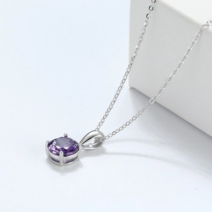 Close-up of circular purple zircon pendant with four-prong setting on a silver chain