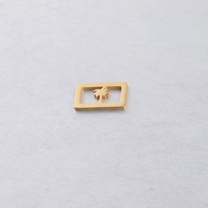 Gros plan d'un pendentif rectangulaire en acier doré avec motif palmier évidé