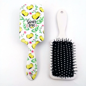 Detail of square air cushion hairbrush featuring floral pattern and white massage bristles