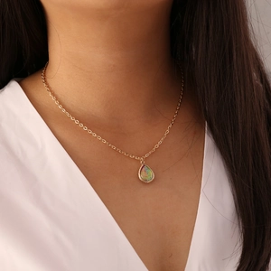 Detalle de un collar dorado con colgante de gota de agua y ópalo de colores en modelo