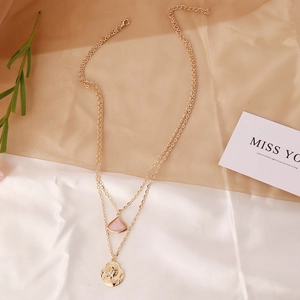 Double-layered gold necklace with pink triangle pendant and vintage portrait coin charm
