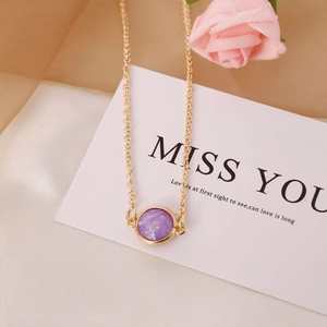 Vintage gold necklace with round purple semi-precious stone pendant on a soft background