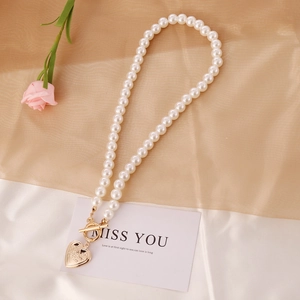 Vintage pearl necklace with golden heart pendant and OT clasp on silk background