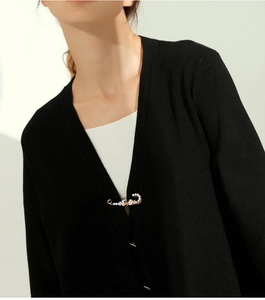 Detail of a gold crystal-encrusted pin brooch styled on a black cardigan neckline